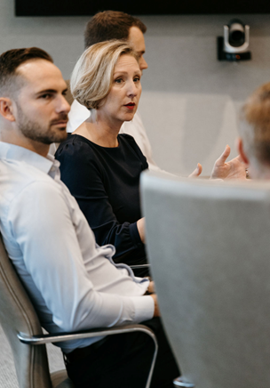 Sitting team members communicating at meeting table.