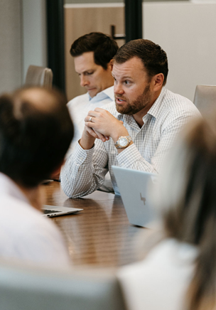 Sitting team members communicating at meeting table.