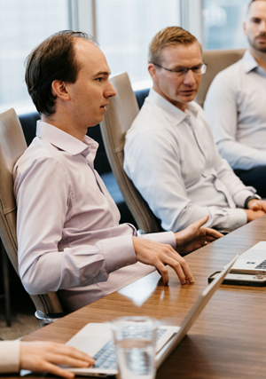 Sitting team members communicating at meeting table.